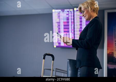 Charmante femme blonde qui s'occupe des billets et à l'aéroport Banque D'Images