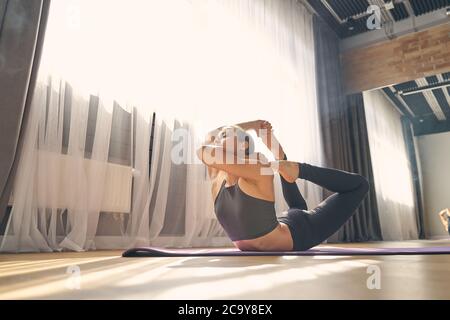 Jeune femme sportive pratiquant le yoga dans un studio privé Banque D'Images