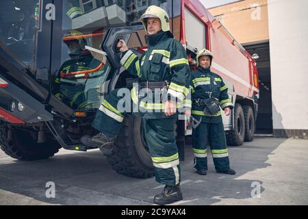 Homme mettant son pied sur le pas d'un gros camion de feu rouge Banque D'Images