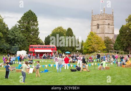 Un village des Cotswolds avec des danseuses Morris sur le terrain de jeu local Banque D'Images