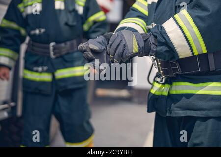 Portrait des mains fortes d'un pompier debout devant un autre homme Banque D'Images