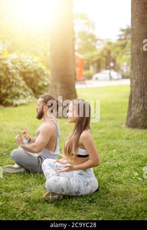 Fitness, yoga, et le style de concept - couple exercices de yoga dans le parc ensoleillé Banque D'Images