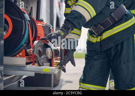 Portrait d'un pompier portant des gants de protection travaillant sur un moteur d'incendie Banque D'Images