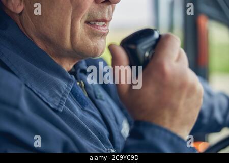 Homme tenant la radio dans sa main tout en étant assis dans le camion d'incendie Banque D'Images