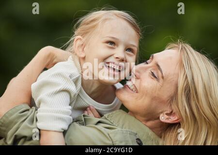 Gros plan portrait d'une mère heureuse jouant avec une petite fille mignonne à l'extérieur tout en s'amusant ensemble dans le parc Banque D'Images