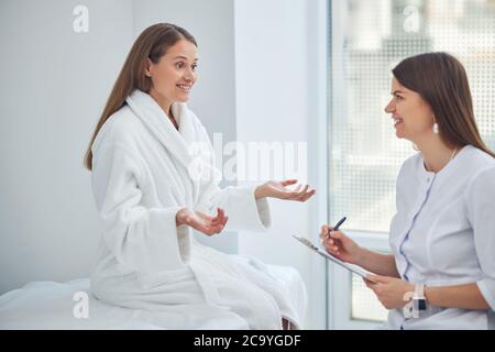 Deux femmes souriantes discutant dans la salle de médecine blanche Banque D'Images