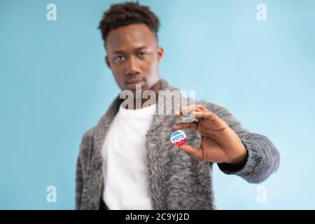 Homme afro-américain avec bouton de vote épinglé sur bleu Banque D'Images