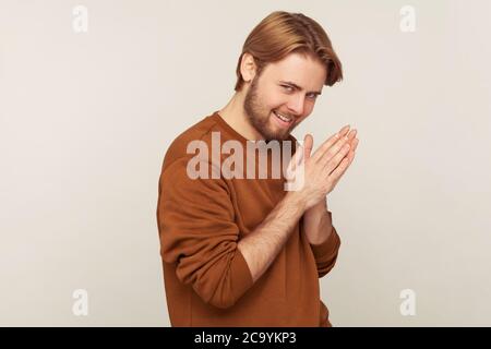 Portrait de l'homme sournois sneaky sneaky scheming avec la barbe portant un sweat-shirt frottant la paume comme ayant funing idée mal, plan sournois à l'esprit, pensant la vengeance. Dans Banque D'Images