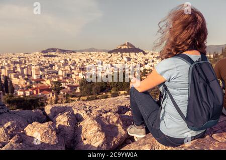Jeune sur fond de paysage urbain d'Athènes, Grèce, Europe. Une jolie fille adulte se détend au sommet d'une colline surplombant la ville d'Athènes en somme Banque D'Images