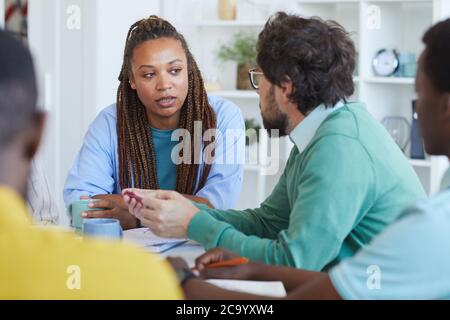 Portrait d'une femme afro-américaine contemporaine parlant à des collègues lors d'une réunion d'affaires au bureau Banque D'Images