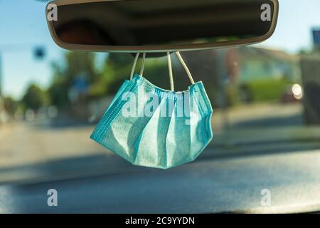 Masque de protection suspendu au rétroviseur dans une voiture Banque D'Images