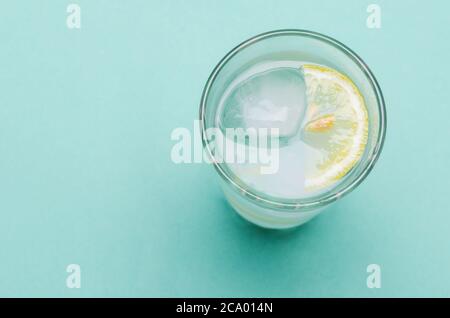 Cocktail avec glace et tranche de citron sur fond bleu vif Banque D'Images