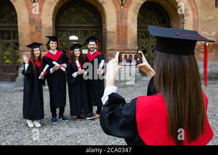 Les jeunes étudiants prennent une photo au téléphone sur le campus après la cérémonie Banque D'Images