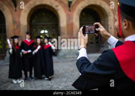 Les jeunes étudiants prennent une photo au téléphone sur le campus après la cérémonie Banque D'Images