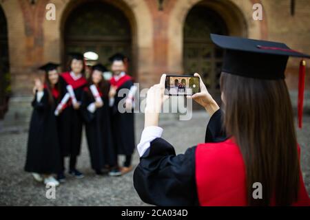 Les jeunes étudiants prennent une photo au téléphone sur le campus après la cérémonie Banque D'Images