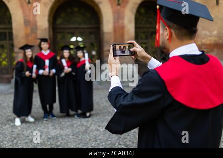 Les jeunes étudiants prennent une photo au téléphone sur le campus après la cérémonie Banque D'Images