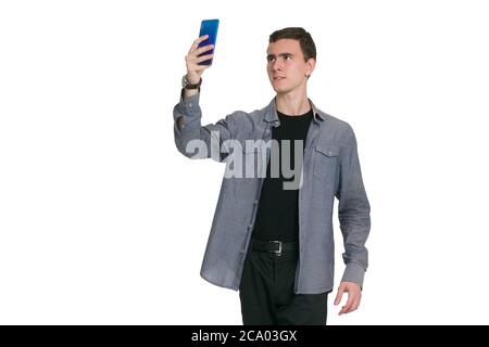 Un jeune homme dans une chemise de Manatee, un t-shirt noir et un pantalon, isolé sur blanc. Prendre des selfies Banque D'Images