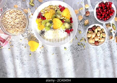 Petit déjeuner sain avec yaourt, granola, fruits frais et noix sur fond clair. Vue de dessus avec espace de copie. Banque D'Images