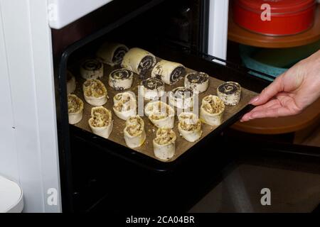 Une femme met au four des curligues farcies de pavot et de noix. Pour la cuisson. Banque D'Images