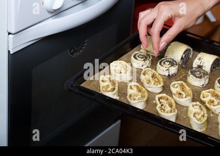 Une femme met au four des curligues farcies de pavot et de noix. Pour la cuisson. Banque D'Images