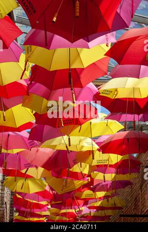 Une grande collection de parasols rouges et jaunes accrochés sur le marché de Camden créant un motif agréable. Londres, Angleterre, Royaume-Uni Banque D'Images