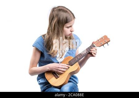 Jeune fille blonde en T-shirt bleu joue de la musique sur l'instrument ukulele. Banque D'Images