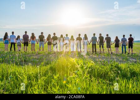 Concept de cohésion. Un groupe d'amis se tient les mains au coucher du soleil. Banque D'Images