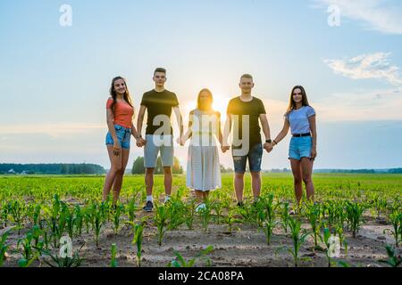 Concept de cohésion. Un groupe d'amis se tient les mains au coucher du soleil. Banque D'Images