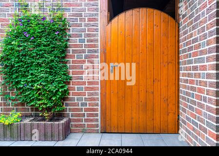 Porte de jardin en bois fermée avec clé à l'intérieur avec poignée noire, mur en brique rouge visible. Banque D'Images