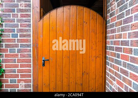 Porte de jardin en bois fermée avec clé à l'intérieur avec poignée noire, mur en brique rouge visible. Banque D'Images