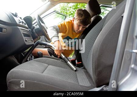 Intérieur de la garniture de voiture de nettoyage d'enfant avec un aspirateur pour gagner de l'argent de poche pendant les vacances scolaires d'été pays de Galles Royaume-Uni KATHY DEWITT Banque D'Images