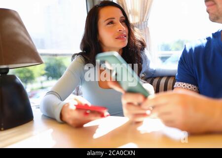 Femme regarde l'homme avec un regard triste et ils tiennent des smartphones dans leurs mains. Banque D'Images