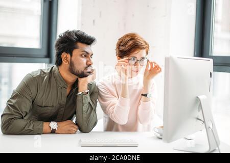 des collègues d'affaires et de femmes inquiets regardant l'ordinateur essayer de résoudre des problèmes au bureau Banque D'Images