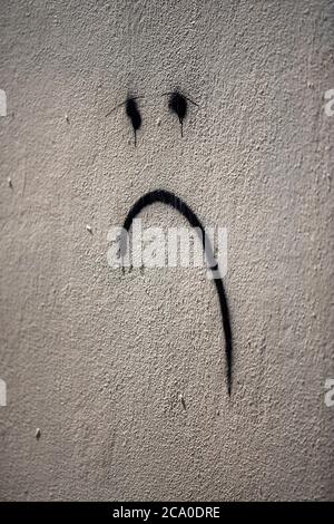 Visage malheureux spray peint sur un mur à Camden, dans le nord de Londres, Angleterre Royaume-Uni Banque D'Images