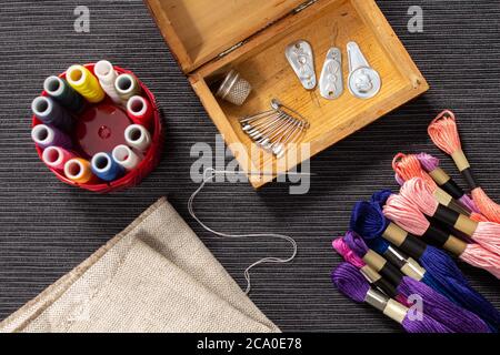 Les accessoires de couture sont dans une boîte en bois. Le mulina et les fils de couleur se trouvent sur la table à côté du cercueil. L'aiguille avec le filetage sur elle repose Banque D'Images