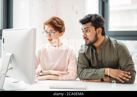 Deux collègues de sexe masculin ont surpris la lecture de nouvelles sur ordinateur au bureau Banque D'Images