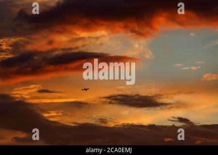 Avion dans le ciel rouge au coucher du soleil Banque D'Images