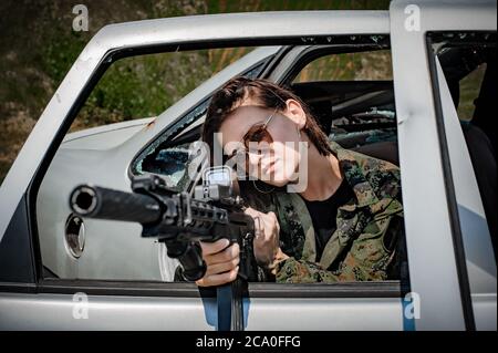 Le soldat féminin attirante avait des cours de tir sur l'aire de tir. Prise de vue à partir d'un entraînement automobile. Femme avec arme. Femme fatale Banque D'Images