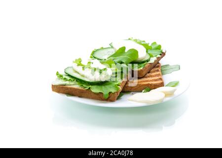 toasts de pain frits avec feuilles de salade, tartinade au fromage et mozzarella dans une assiette isolée sur fond blanc Banque D'Images