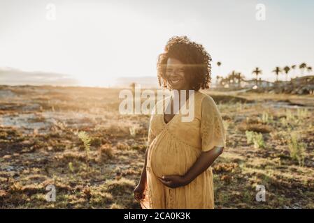 Portrait de la mère enceinte au troisième trimestre à la plage à coucher de soleil Banque D'Images