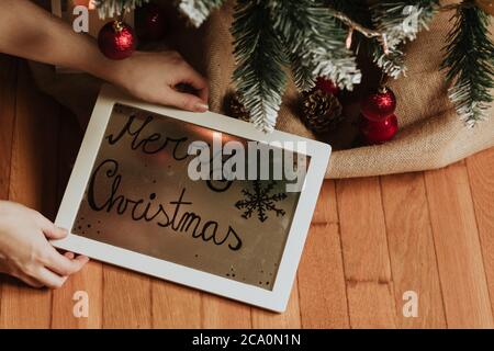 Recadrez la femme mettant le cadre sous l'arbre de noël Banque D'Images