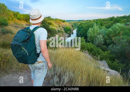 un gars dans un t-shirt et avec un sac à dos voyage à travers les montagnes du canyon et regarde le coucher du soleil Banque D'Images