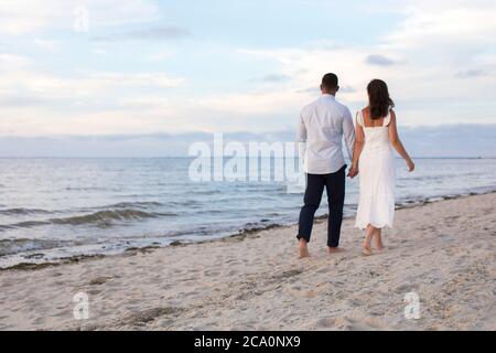 couple romantique de derrière marche à la plage main dans la main Banque D'Images