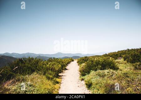 chemin en pierre entouré de végétation contre les montagnes et le ciel bleu Banque D'Images