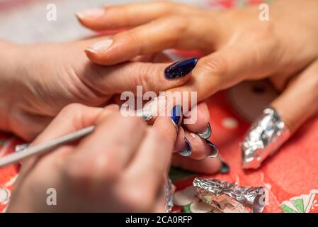 Close-up de la main d'un manucure ongles qualifiés le dépôt d'une jeune femme. Banque D'Images