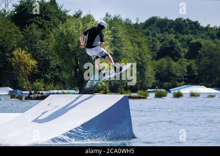 saut en planche avec le wakeboard au parc wake, tout en glissant dans les airs au milieu de l'astuce de saut à ski Banque D'Images