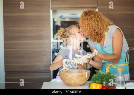 Joyeux cacaucasien maman et fille préparant la boulangerie ensemble, la cuisine de pizza et de s'amuser dans la cuisine. Couple aimant embrassant, embrassant avec ha Banque D'Images
