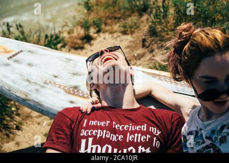 ODESSA, UKRAINE - MAI, 20 2015: Mignon jeune hipster couple de surfeurs avec surf faisant plaisir et plaisantant, couché sur l'herbe Banque D'Images