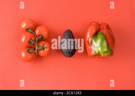 Mise en page faite d'avocat, de tomate et de poivre. Concept alimentaire. Légumes sur fond rouge. Concept d'été minimal. Motif végétal. Banque D'Images