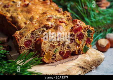 Gâteau traditionnel aux fruits de Noël sur une planche de bois dans une décoration de fête, fond sombre. Banque D'Images